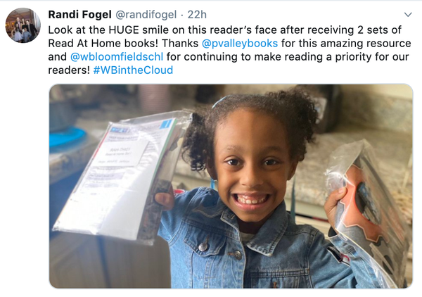 Student with huge smile holding up Read at Home books